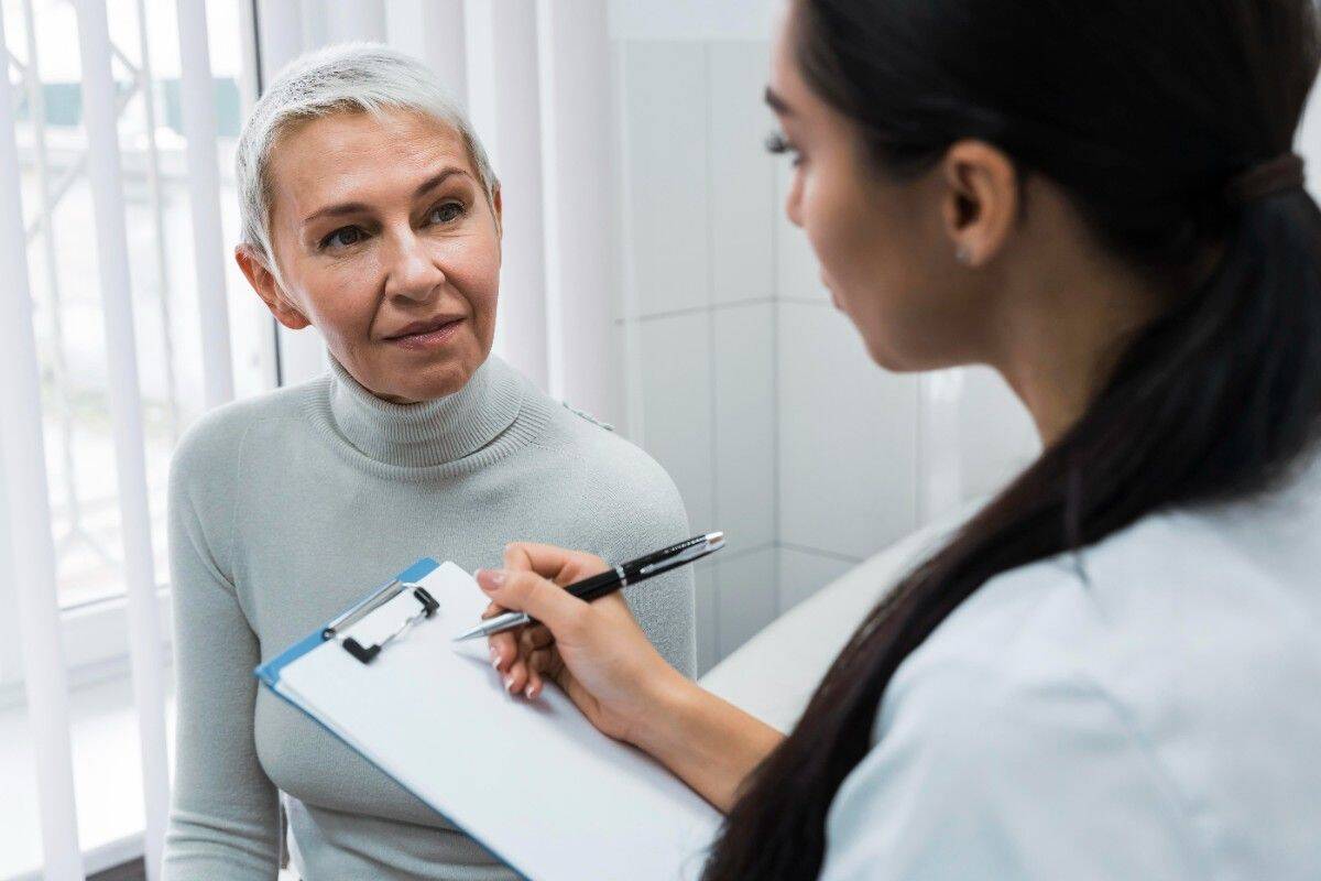 Dentist examining smiling patient’s teeth in dental clinic