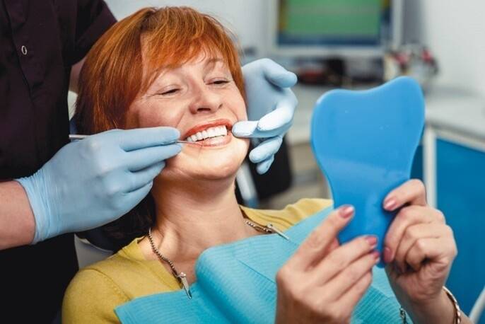 Patient checking smile in mirror during dental treatment
