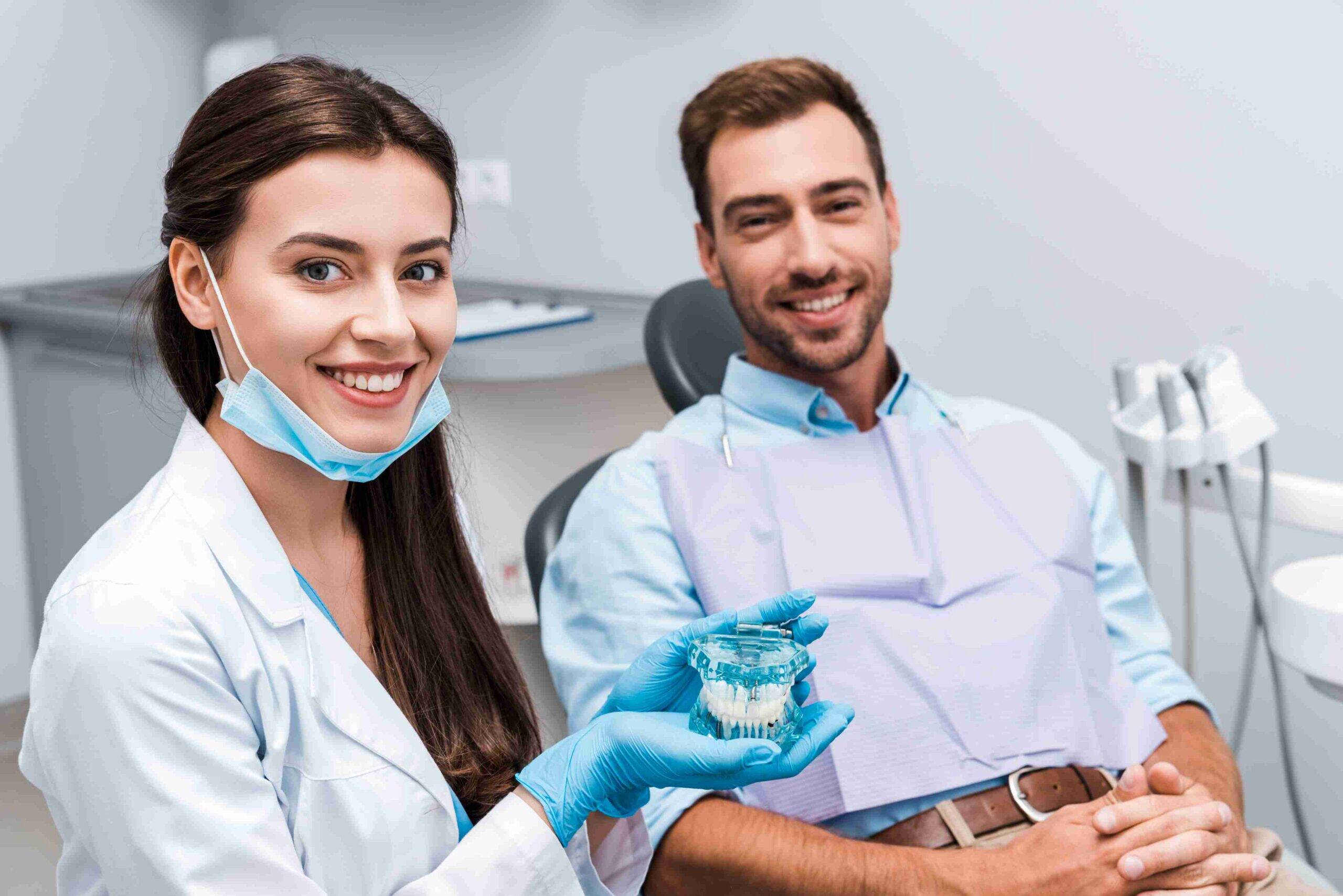 Dentist showing a dental model to a smiling patient during consultation.