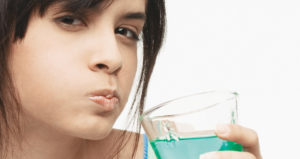 A Girl Gargle a Mouthwash to Clean her Teeth