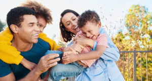 A young family of four all laughing and playing together