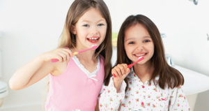Two young girls brushing their teeth